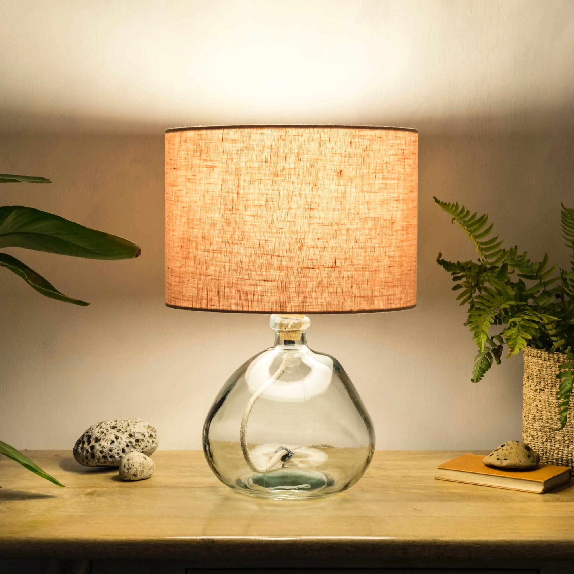 Blush pink lampshade on recycled glass base illuminated at night