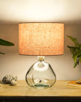 Blush pink lampshade on recycled glass base illuminated at night